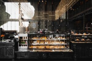 ตู้โชว์ขนมหวานและบรรยากาศภายในร้าน Davin Cafe สไตล์อินดัสเทรียล พร้อมเคาน์เตอร์หินอ่อนและประติมากรรมคลาสสิก