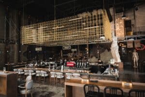ภาพภายในร้าน Davin Cafe กับบาร์สไตล์อินดัสเทรียล เครื่องชงกาแฟเอสเปรสโซ่ โต๊ะหินอ่อน ประติมากรรมคลาสสิก และบรรยากาศอบอุ่นในพื้นที่เพดานสูง
