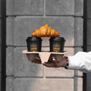เซตกาแฟใส่ถาดจาก Davin Cafe พร้อมครัวซองต์สีทองวางบนแก้วกาแฟสองใบ พื้นหลังเป็นกำแพงหินสีเทา