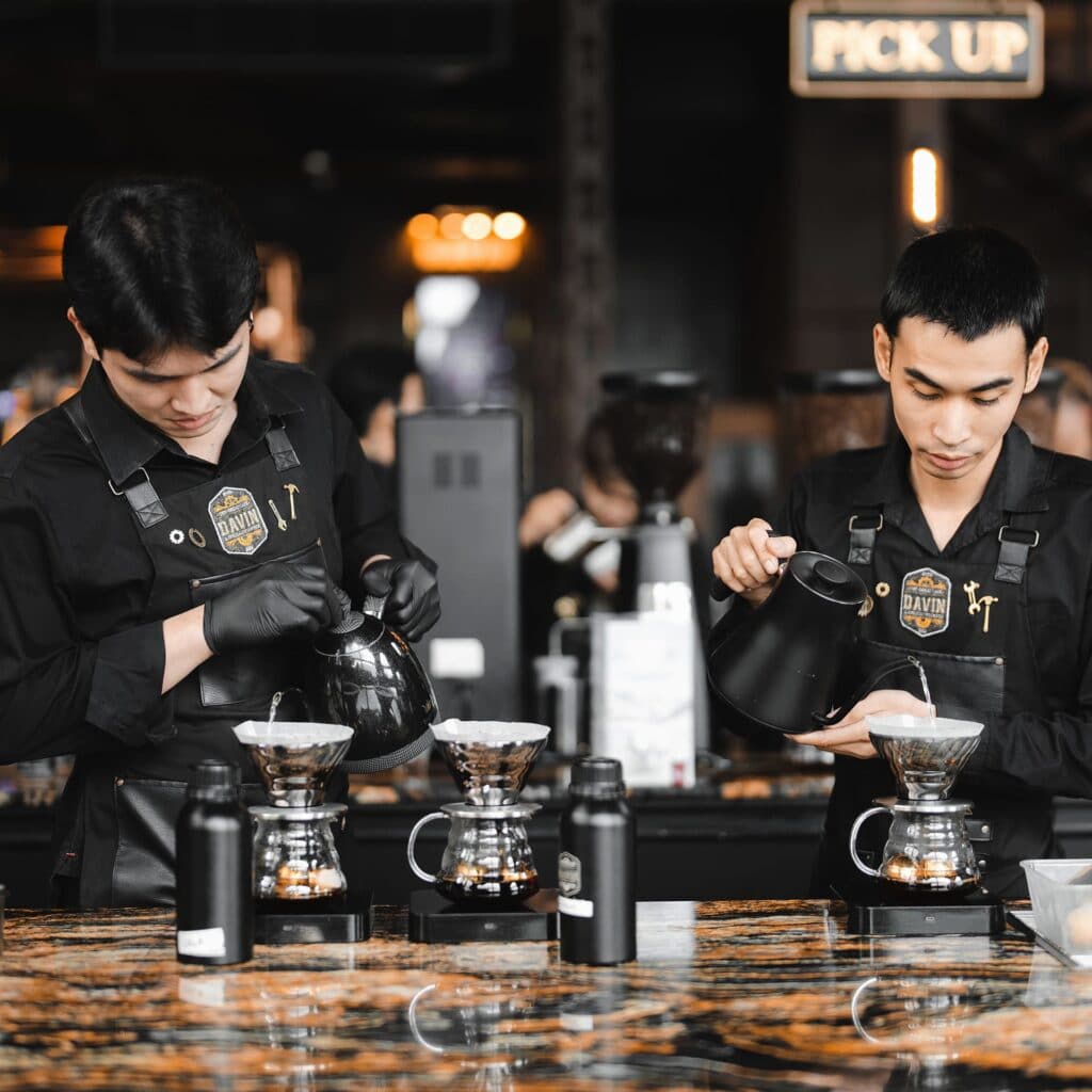 บาริสต้าสองคนจาก Davin Cafe กำลังชงกาแฟดริปอย่างพิถีพิถันด้วยกาดริปที่เคาน์เตอร์.