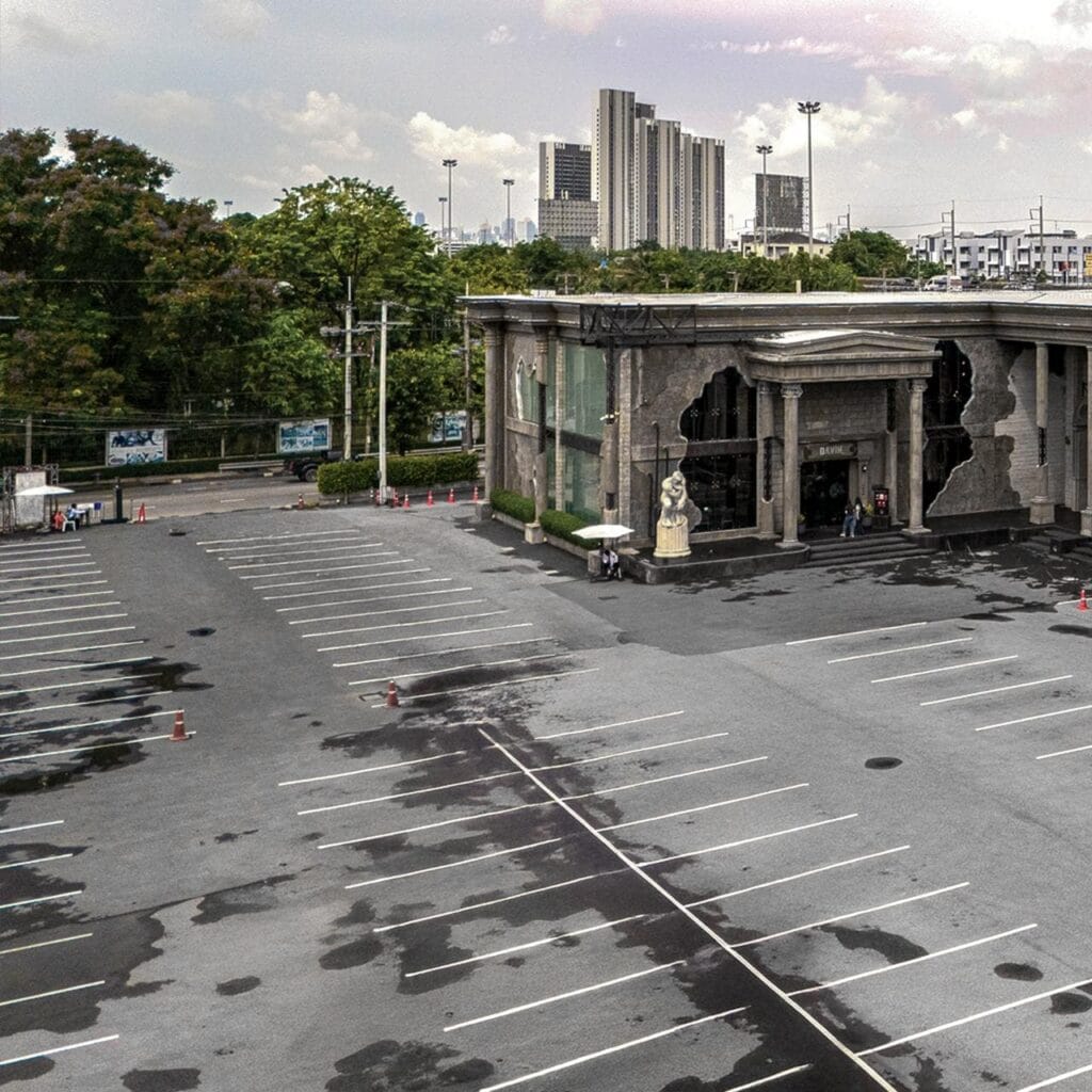 The unique, weathered facade of the Davin building with an empty parking lot in the foreground and a city view in the background.