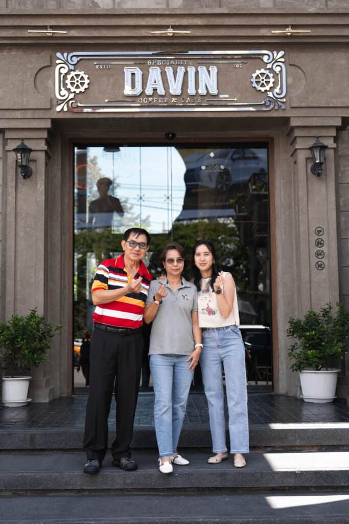 ภาพถ่ายครอบครัวสามคนกำลังยืนถ่ายรูปที่ทางเข้าร้าน Davin Cafe.