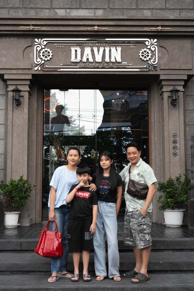 ภาพถ่ายครอบครัวสี่คนกำลังยืนถ่ายรูปหน้าทางเข้าร้าน Davin Cafe.