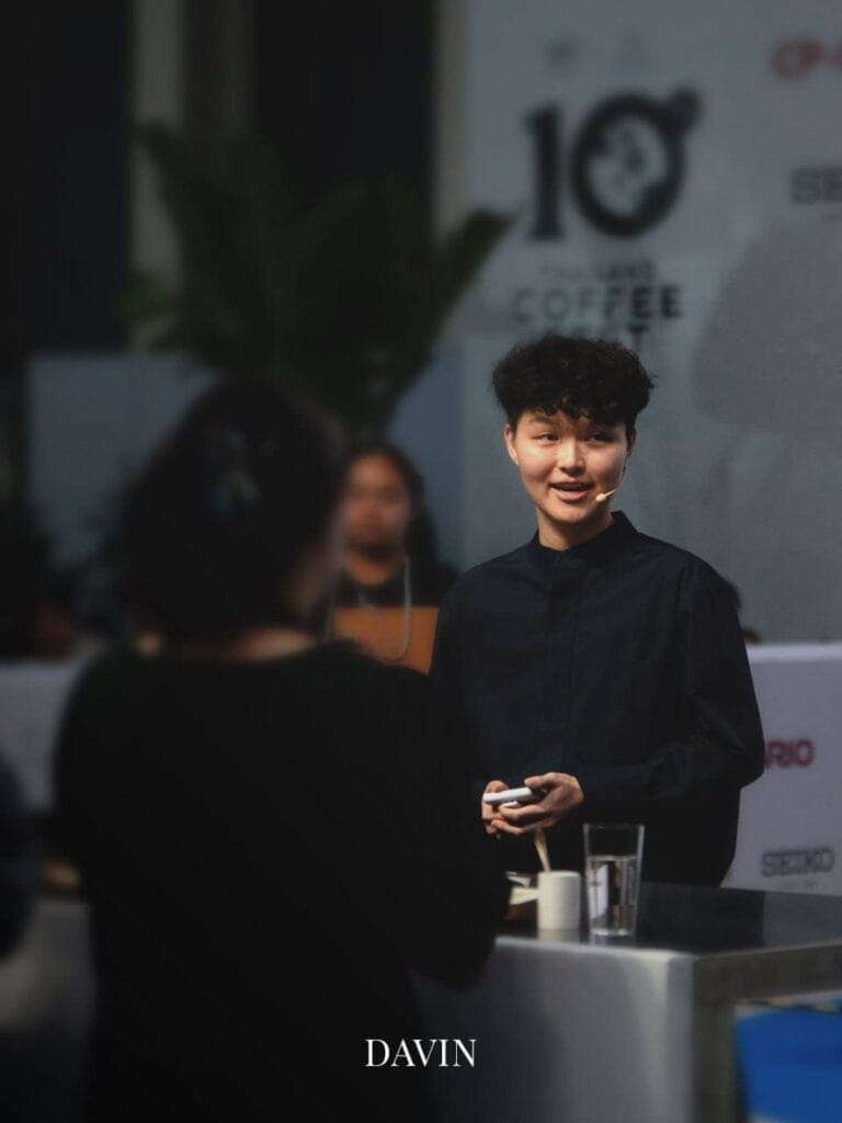 เจน-กวินนาร์ท ผู้เชี่ยวชาญด้านกาแฟกำลังยิ้มและนำเสนอในงานกาแฟ.