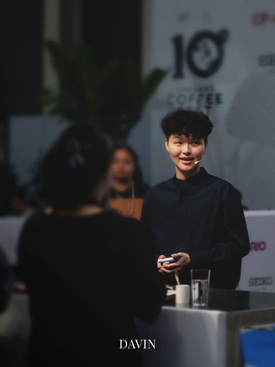 เจน-กวินนาร์ท ผู้เชี่ยวชาญด้านกาแฟกำลังยิ้มและนำเสนอในงานกาแฟ.