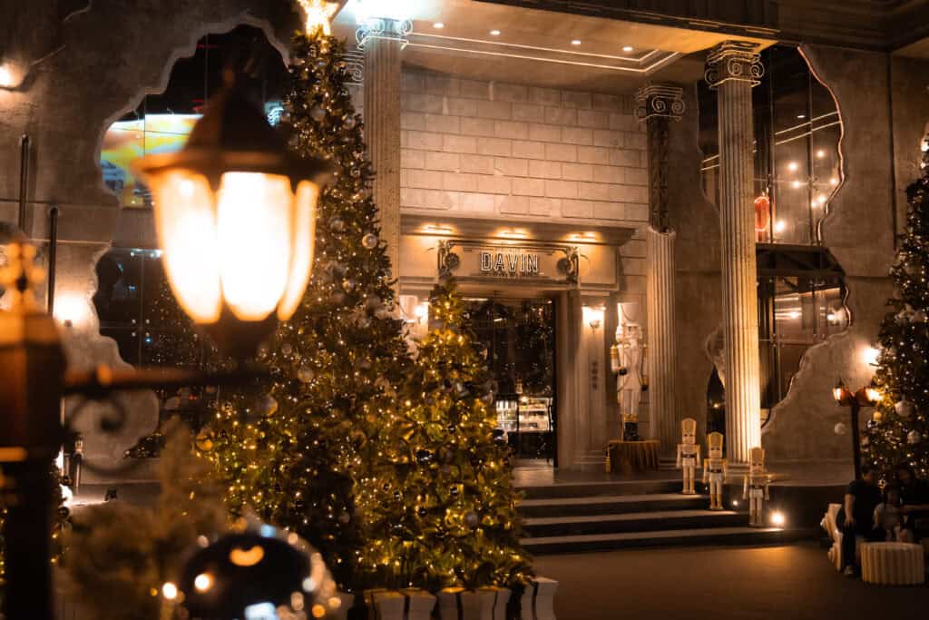 A luxury event venue decorated for Christmas 2025 at night, featuring illuminated Christmas trees, warm festive lighting, and classic architectural design, ideal for Christmas celebrations, year-end parties, and premium holiday events