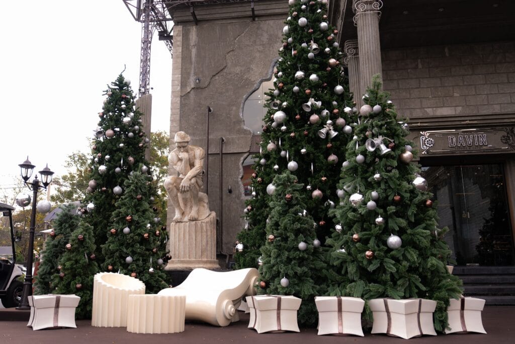An outdoor Christmas 2025 venue decoration featuring large Christmas trees, sculptural elements, and elegant festive details, creating a refined welcoming space for Christmas celebrations, year-end events, and premium holiday gatherings