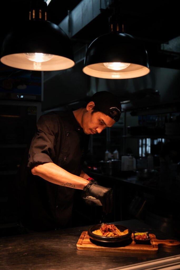 เชฟของ Davin Cafe กำลังจัดจานอาหารอย่างประณีตในครัวเปิด สะท้อนประสบการณ์ดินเนอร์ที่ใส่ใจทุกรายละเอียด ตั้งแต่การปรุงจนถึงการเสิร์ฟในบรรยากาศพรีเมียม