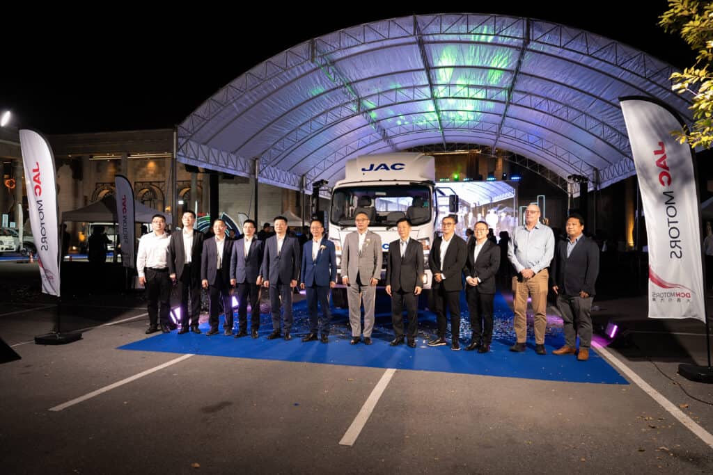 A professional event venue hosting a corporate product launch with a full production stage, lighting system, and executive group photo during an official ceremony