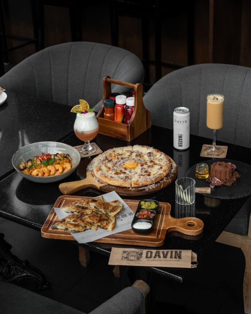 A photogenic cafe table featuring beautifully styled pizza, European dishes, and drinks in a modern industrial setting, ideal for lifestyle photography and content creation