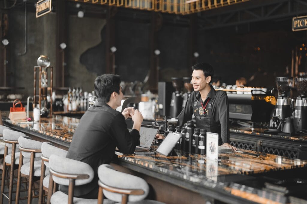 บาริสต้าให้บริการและพูดคุยกับลูกค้าที่เคาน์เตอร์ของร้านกาแฟ รามอินทรา Davin Cafe บรรยากาศอบอุ่นและเป็นกันเอง