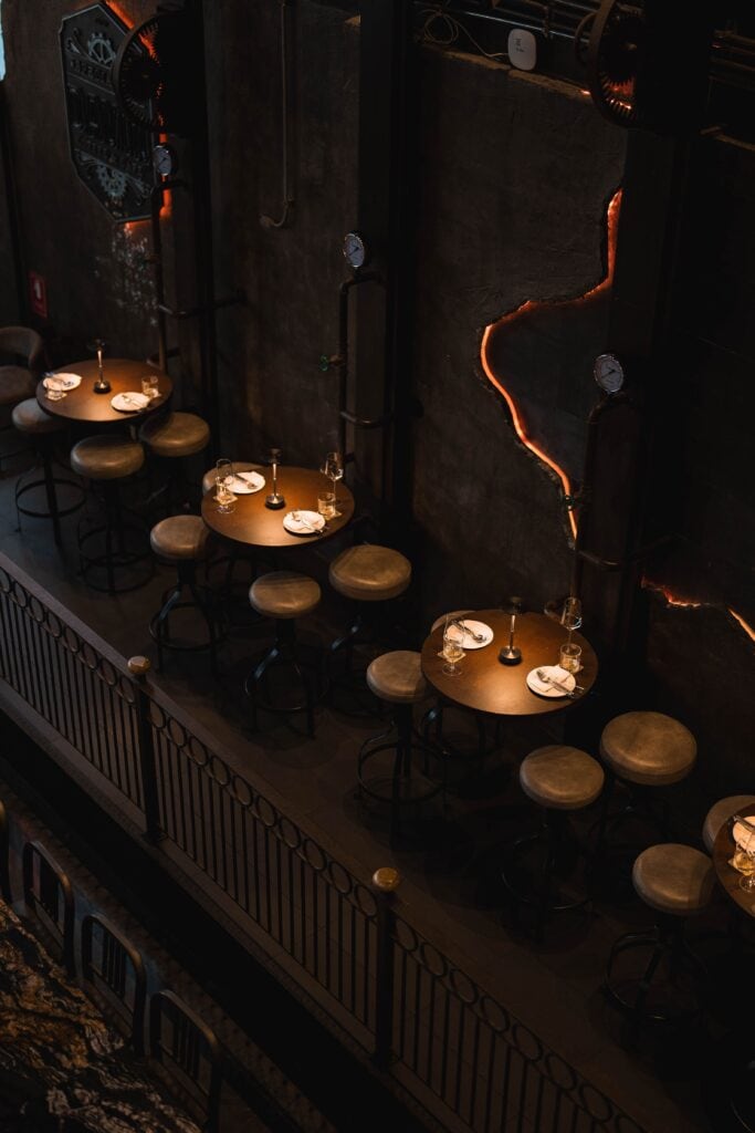 An industrial-style seating area inside Davin Cafe, a cafe along the Ramintra Expressway, featuring intimate tables and moody lighting designed for private conversations, casual meetings, and refined café experiences.