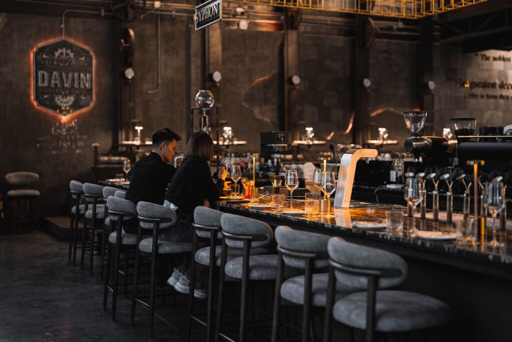 คู่รักนั่งดินเนอร์ที่เคาน์เตอร์บาร์ของ Davin Cafe ท่ามกลางแสงไฟโทนอุ่นและบรรยากาศเงียบสงบ ให้ฟีลดินเนอร์สุดโรแมนติก เหมาะสำหรับการใช้เวลาคุณภาพร่วมกันในช่วงค่ำ