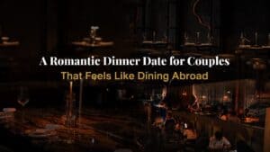 A couple enjoying an intimate dinner at the bar counter of Davin Cafe, surrounded by warm lighting and an elegant industrial interior, creating a refined evening dining experience ideal for romantic moments and relaxed conversations.