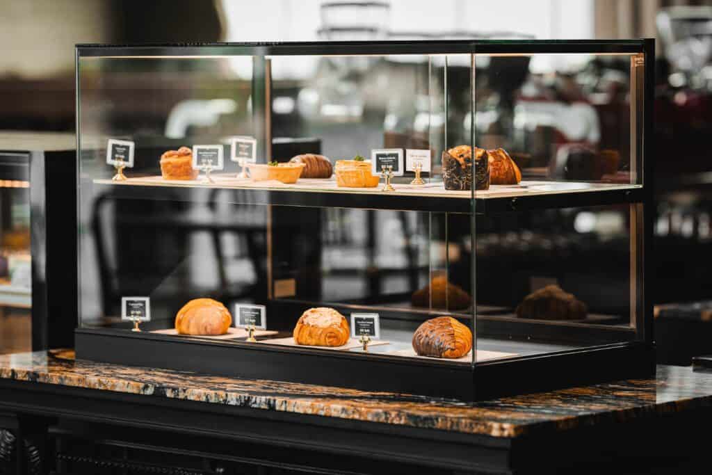 Glass pastry showcase at Davin Cafe featuring freshly baked croissants and artisanal pastries on a marble counter, highlighting the craftsmanship and premium experience that define a leading bakery Bangkok destination.