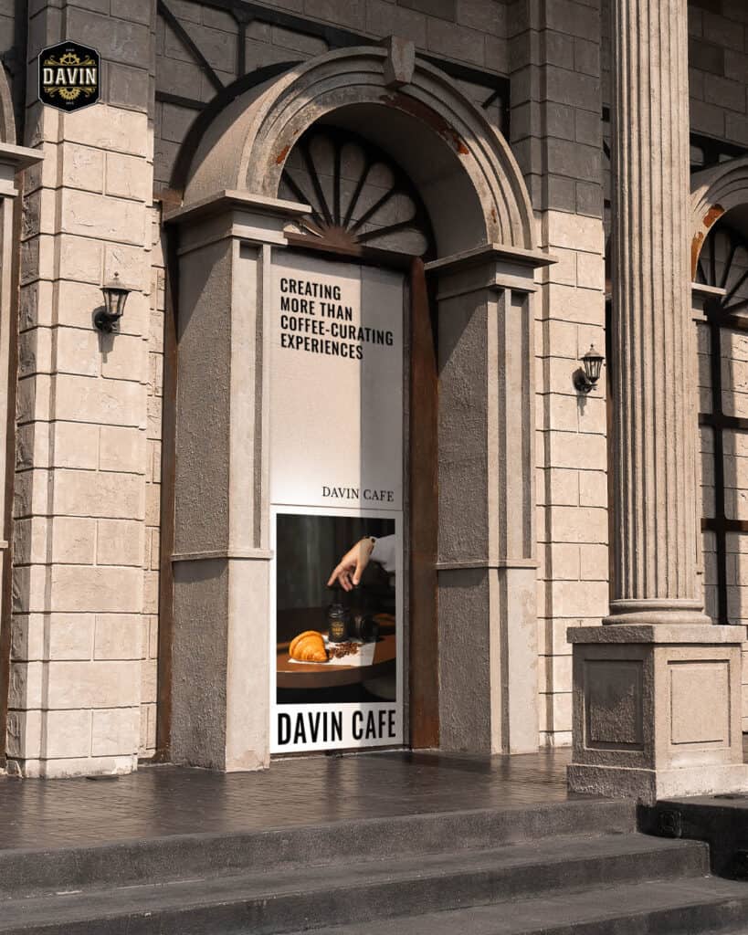 Arched architectural entrance of Davin Cafe on Pradit Manutham Road featuring a specialty coffee campaign poster—positioning the venue as more than a café, but a curated dining and event destination in the Praditmanutham district.