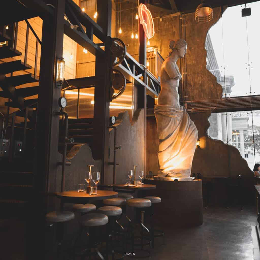 Industrial-classic interior at Davin Cafe on Pradit Manutham Road featuring a sculptural focal point and warm ambient lighting—an atmospheric dining and private event space in the Praditmanutham area of Bangkok.