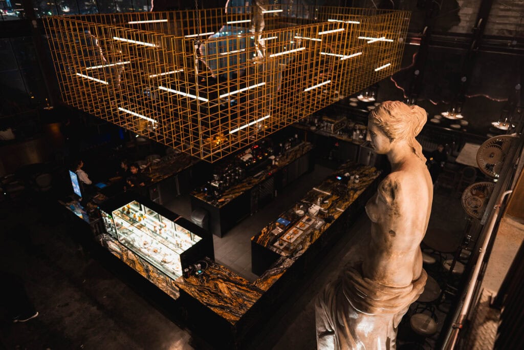 Overhead view of Davin Cafe in Ramintra showcasing a European-inspired interior with marble bar counters, statement sculpture, and ambient lighting—an upscale neighborhood café ideal for those searching for a distinctive café near me experience.