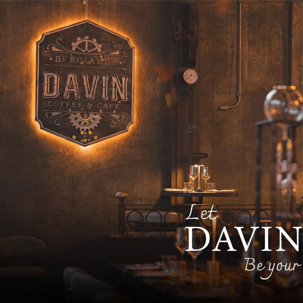 ป้ายโลโก้ Davin Coffee & Cafe บนผนังสไตล์ลอฟต์แสงไฟวอร์มโทน สร้างบรรยากาศอบอุ่นและหรูหรา สะท้อนตัวตนของ bakery bangkok ที่ให้ความสำคัญทั้งรสชาติและประสบการณ์ภายในร้าน