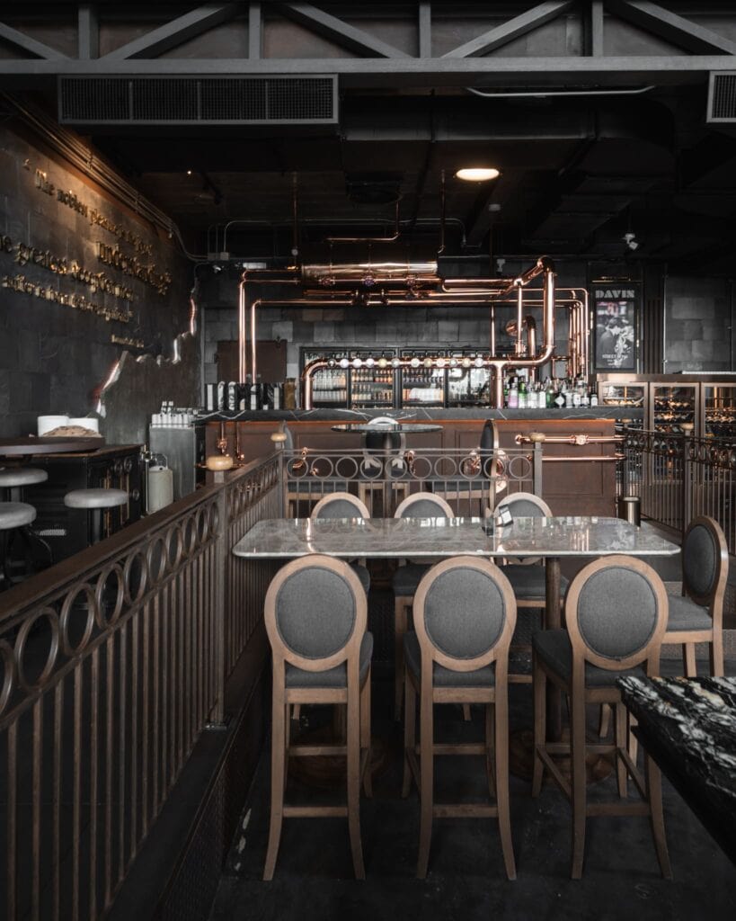 โซนที่นั่งภายในร้านกาแฟเลียบด่วน รามอินทรา Davin Cafe ตกแต่งสไตล์อินดัสเทรียล มีเคาน์เตอร์บาร์ทองแดงและโต๊ะหินอ่อน บรรยากาศพรีเมียม เหมาะสำหรับนั่งประชุมหรือพบปะสำคัญ