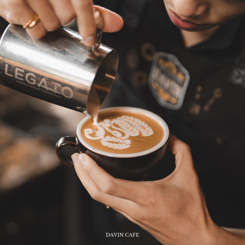Barista creating specialty latte art at Davin Cafe, a coffee shop along Liab Duan Ramintra in Bangkok known for high-quality handcrafted coffee