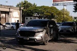 รถยนต์ดำจอดในลานจอดรถหน้าร้าน Davin Cafe พร้อมฉากต้นไม้และอาคารในพื้นหลัง.