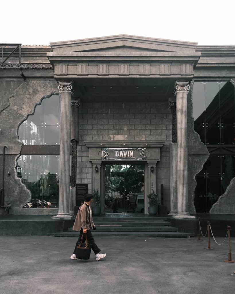 ด้านหน้าทางเข้า Davin Cafe คาเฟ่กรุงเทพสไตล์ยุโรปที่โดดเด่นด้วยเสาหินคลาสสิกและสถาปัตยกรรมขนาดใหญ่ ผู้คนเดินเข้าร้านเพื่อสัมผัสบรรยากาศคาเฟ่และกาแฟคุณภาพในย่านรามอินทรา