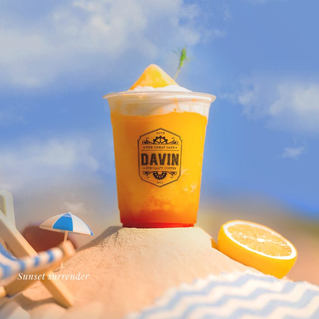 'Golden Hour', a signature summer cocktail with vibrant purple and orange layers, garnished with cherry and fresh mint, showcasing Davin Cafe's mixology expertise.