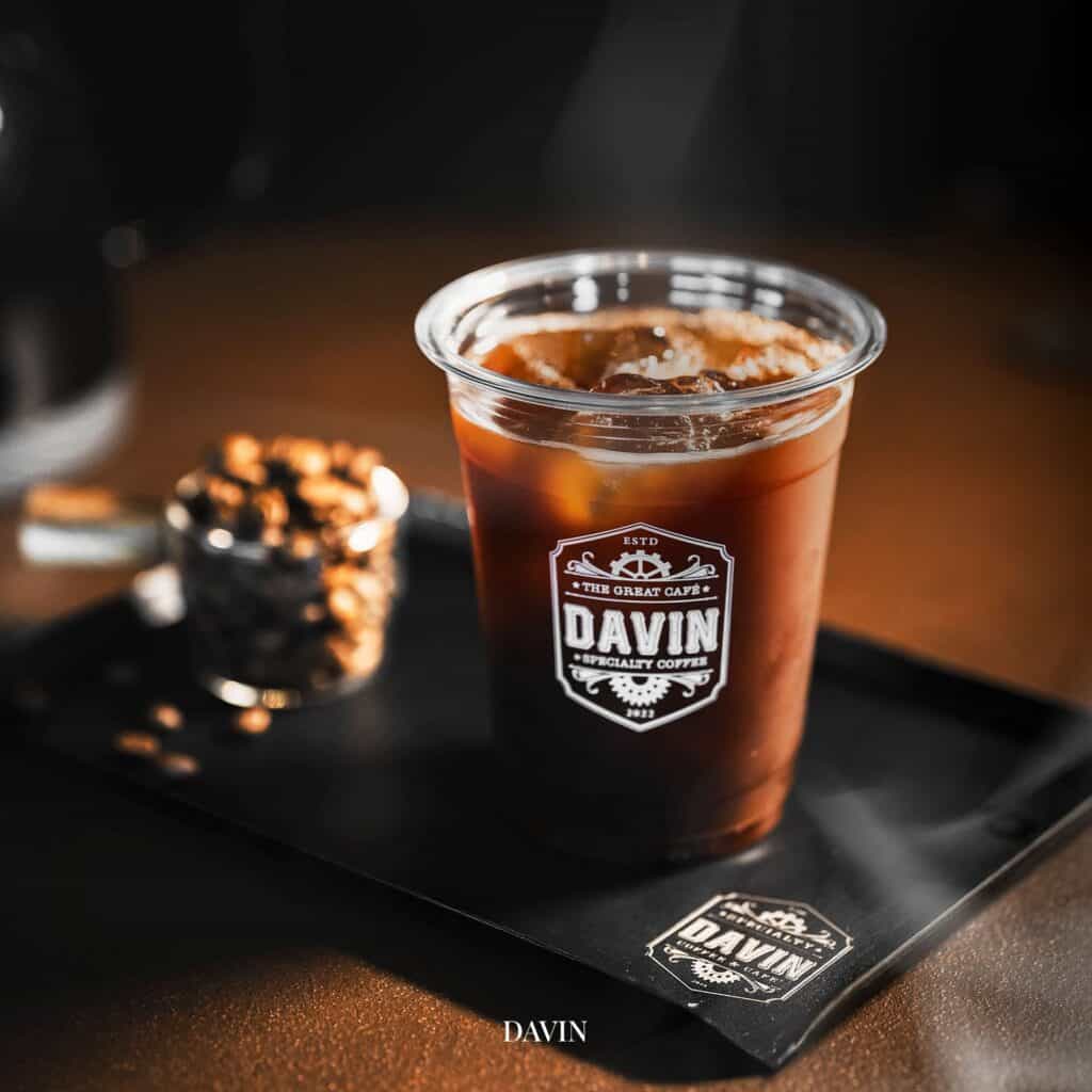 Iced Americano served at Davin Cafe in Bangkok, presented on a tray with coffee beans in the background, reflecting the aesthetic presentation and specialty coffee culture of a stylish coffee shop.