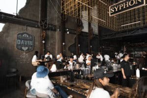 ดินแดนกาแฟและบรรยากาศในร้าน Davin Cafe ที่มีลูกค้านั่งสั่งเครื่องดื่มและสนุกสนานในบรรยากาศสไตล์อุตสา.