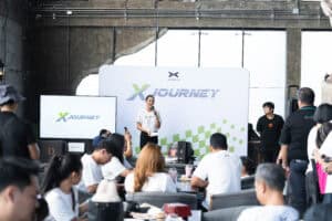 Davin Cafe, X Journey event with speaker and audience in industrial-style venue, July 2025.