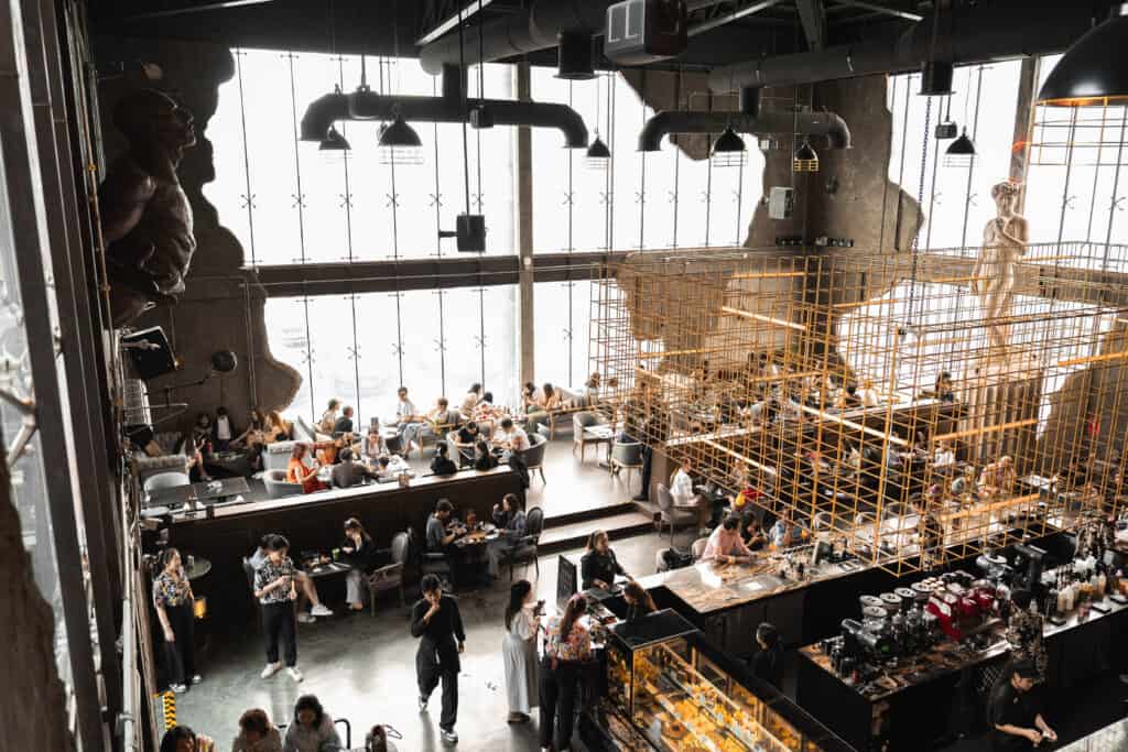 A wide overhead view of Davin Cafe showing a spacious interior filled with guests during Songkran, offering a comfortable and stylish indoor escape from the heat in Bangkok