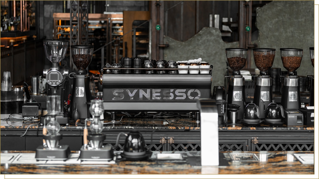 Professional specialty coffee station at Davin Cafe featuring a Synesso espresso machine and industrial grinders, perfect for high-quality coffee catering and artisan brew experiences.
