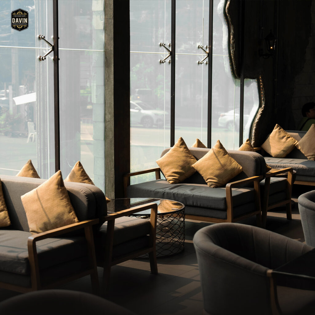 มุมนั่งโซฟาริมกระจกภายใน Davin Cafe ร้านกาแฟ กรุงเทพ ที่ให้บรรยากาศผ่อนคลาย แสงธรรมชาติสวย และพื้นที่นั่งเป็นสัดส่วน เหมาะสำหรับพักจิบกาแฟ นัดคุยงาน หรือใช้เป็นมุมรับรองในงานจัดเลี้ยงแบบพรีเมียม