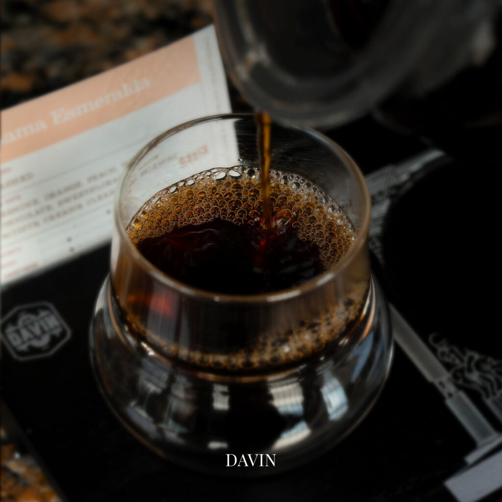 กาแฟดำกำลังถูกเสิร์ฟลงแก้วที่ Davin Cafe ร้านกาแฟ กรุงเทพ ที่ใส่ใจรายละเอียดของเมล็ดกาแฟ การสกัดรสชาติ และประสบการณ์เครื่องดื่มคุณภาพ เหมาะสำหรับผู้ที่มองหาคาเฟ่พร้อมอาหารและพื้นที่รองรับการจัดเลี้ยงในบรรยากาศพิเศษ