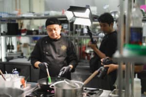 เชฟกำลังถ่ายทำคอนเทนต์อาหารในสตูดิโอ DAVIN CAFE พร้อมไฟโปรดักชันระดับมืออาชีพ เหมาะสำหรับรายการอาหาร รีวิวร้าน และ branded content