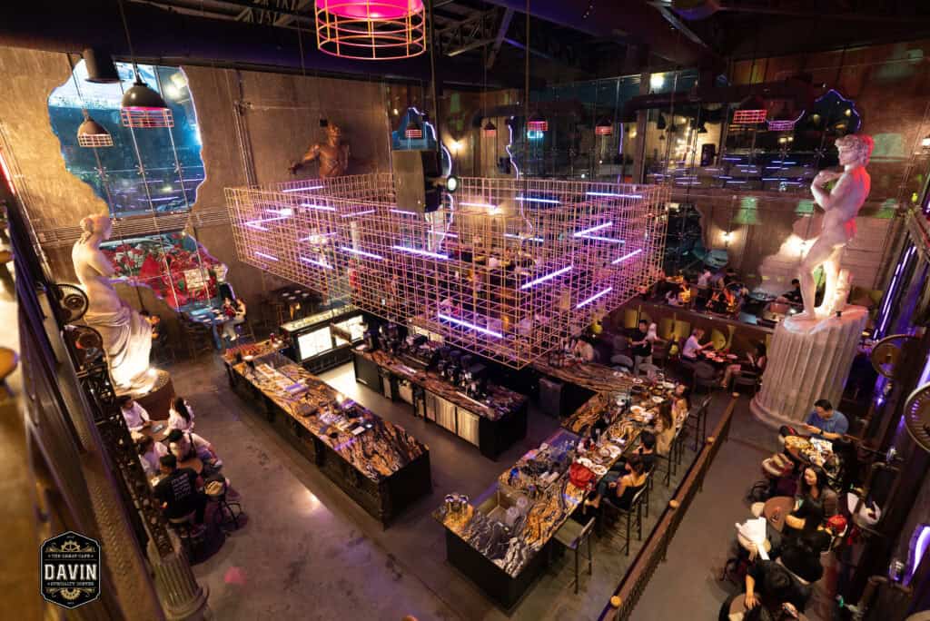 High-angle view of Davin Cafe’s spacious bar and event area, showcasing a Bangkok fan meet venue with multiple seating zones, dramatic lighting, distinctive interiors, and full food and beverage support for artist gatherings, mini concerts, and private fan events.