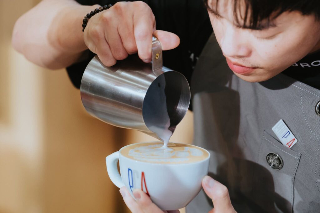 DAVIN CAFE barista demonstrating precision milk pouring and latte art creation during PCA Latte Art Thailand 2026, showcasing specialty coffee expertise, professional craftsmanship, and competition-level barista performance