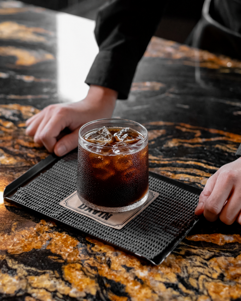 Cold Brew ซิกเนเจอร์จาก DAVIN CAFE เสิร์ฟพร้อมน้ำแข็งในแก้วเย็น แสดงเอกลักษณ์ของกาแฟสกัดเย็นที่ให้รสชาตินุ่มลึก หวานธรรมชาติ และกลิ่นหอมชัดเจน เหมาะสำหรับผู้ที่มองหาประสบการณ์ Specialty Cold Brew ระดับพรีเมียม