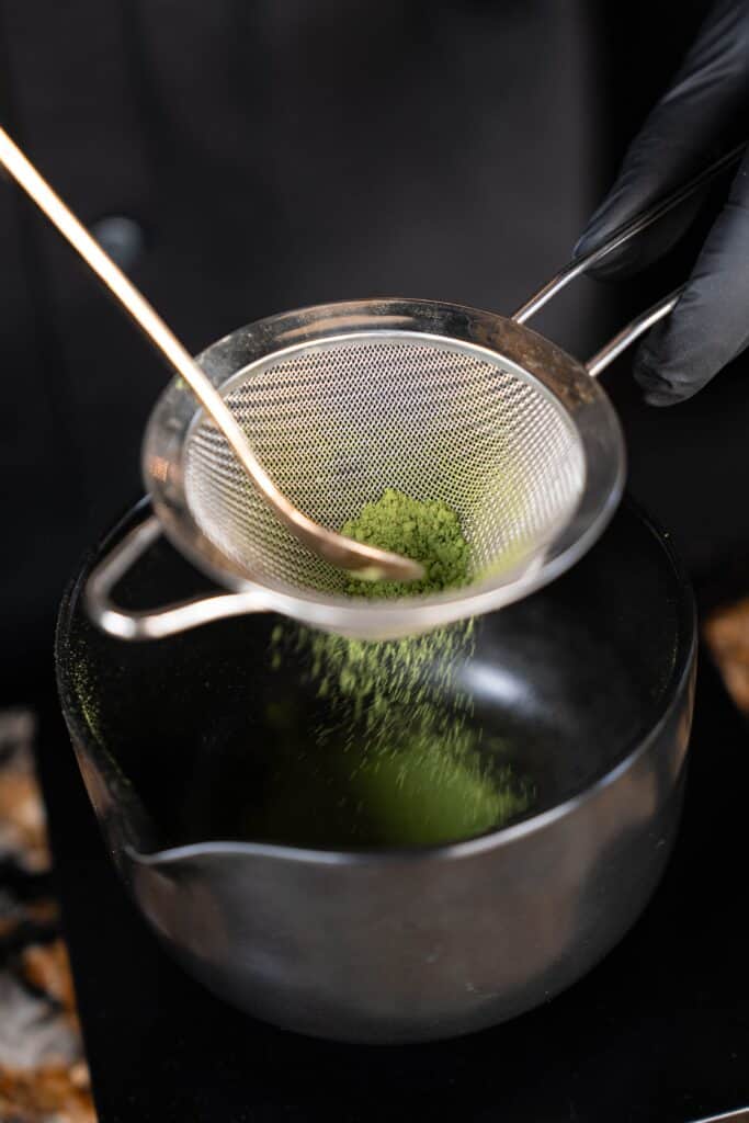 Ceremonial-grade matcha powder being carefully sifted for Matcha Latte at DAVIN CAFE Bangkok, ensuring a smooth texture, vibrant green color, and authentic Japanese matcha flavor in every cup.