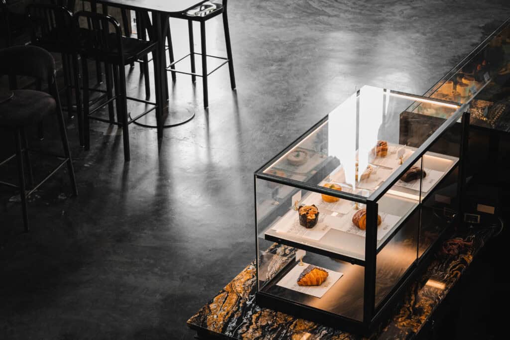 Pastry counter and quiet seating area at Davin Cafe in Ramintra, featuring a glass bakery display, natural light, and a calm interior for guests looking for a work-friendly cafe with coffee, desserts, and a focused daytime atmosphere.