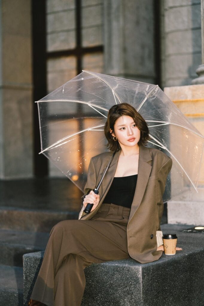 ท่าโพสถ่ายรูปคาเฟ่แบบนั่งถือร่มใส ลุคแฟชั่น Modern Luxury ข้างแก้วกาแฟและสถาปัตยกรรมสไตล์โรมันที่ DAVIN CAFE รามอินทรา