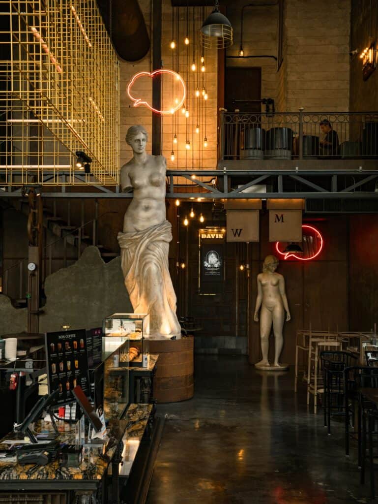 European-inspired interior of DAVIN CAFE, a rainy day cafe in Ramintra featuring classical statues and warm ambient lighting
