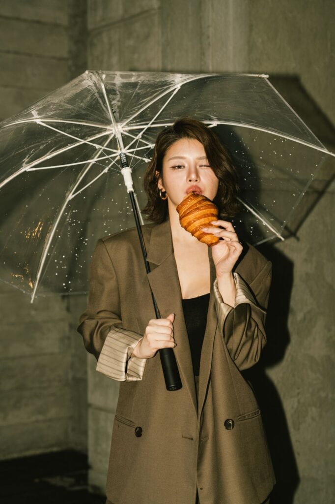 Rainy day cafe in Ramintra at DAVIN CAFE with a woman holding a clear umbrella and croissant outside the cafe