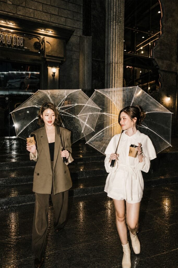 Rainy day cafe in Ramintra at DAVIN CAFE with two women holding clear umbrellas and coffee outside the European-style cafe