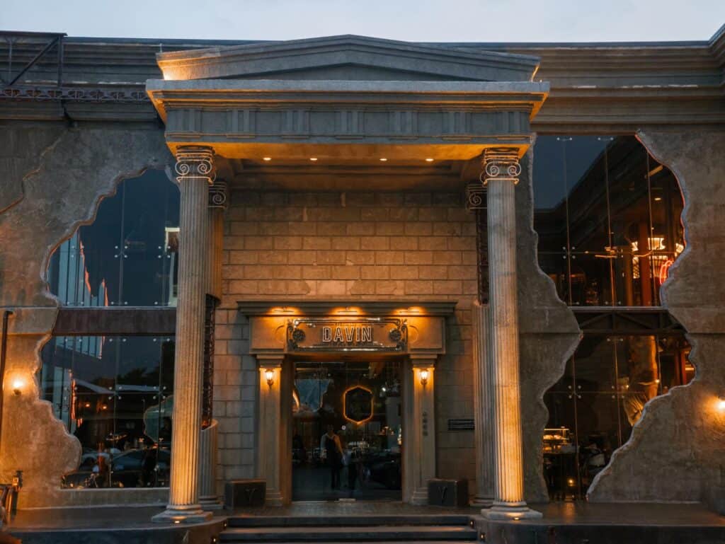 สถาปัตยกรรมด้านหน้า DAVIN CAFE คาเฟ่ Golden Hour รามอินทรา โดดเด่นด้วยเสาโรมันและแสงไฟอบอุ่นช่วงเย็น